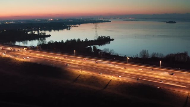 Evening traffic on the A6 highway that connects Amsterdam and the main land to the Flevoland polder with Almere and Lelystad cities in The Netherlands. Aerial shot.	