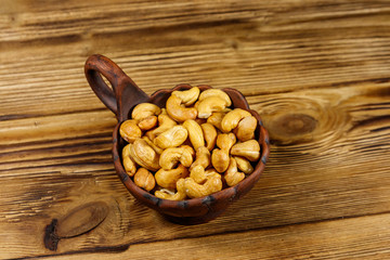 Ceramic bowl with roasted cashew nuts on a wooden table