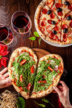 Italian food. Pizza for Valentine's Day for lovers in the form of a heart. Two glasses of red wine stand on the table. Romance in a restaurant for two. background image, copy space text