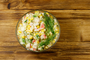 Salad with crab sticks, sweet corn, cucumber, eggs, rice and mayonnaise on wooden table. Top view
