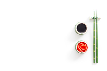 Set of chopsticks for sushi, ginger and soy sause on white background top-down frame copy space