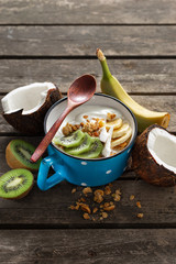 Delicious coconut yogurt with granola and fruit served on  rustic wooden table. Healthy vegan food. Tasty and healthy breakfast concept