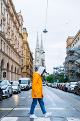 Naklejka premium woman crossing street old church towers on background
