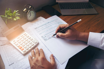 Budget planning concept, Accountant is calculating company's annual tax. Calendar 2020 and personal income tax forms for those who have income under US law placed on office desk. - obrazy, fototapety, plakaty