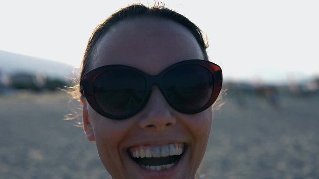Portrait of a girl smilling in the camera and spinning with it on the beach