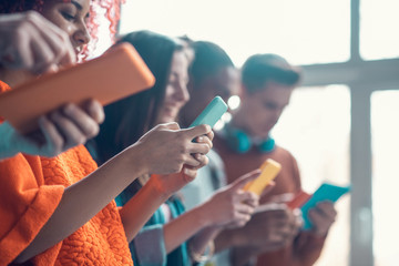 Students holding colorful smartphones while having break from study
