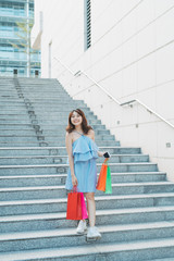Asian young smile woman enjoy shopping with colorful bag while going down stairs.