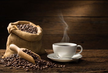Tasse de café avec de la fumée et des grains de café sur fond de bois ancien