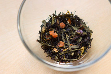 Fototapeta premium dry tea mix with herbs and fruit slices in a transparent cup, bowl, mug