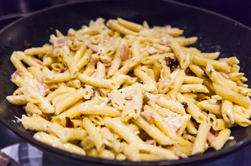 Delicious Creamy White Sauce Hearty Bacon Garlic Penne Pasta in frying skillet pan. Italian Pasta Dish, Gastronomy, Delicacy, Cuisine, Food, Meal, Dinner and Recipe concept
