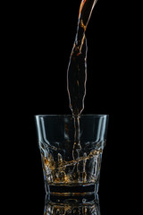 Glasses of whiskey with splash, isolated on black background