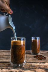 Cold coffee with ice and milk on a wooden table