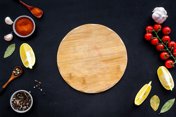 Mockup for menu. Cutting board near spices and vegetables on black background top-down