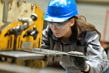 Young apprentice using steelworks machine - obrazy, fototapety, plakaty
