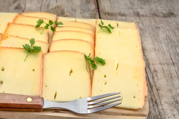 Foto op Plexiglas tranches de fromage à raclette sur une planche à découper © ALF photo