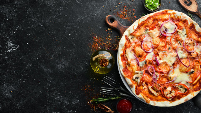 Homemade pizza on a black stone background. Italian cuisine. Top view. Free space for your text.