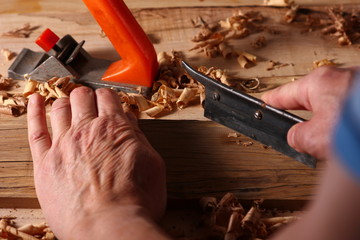 process of planing a wooden board with a hand plane in a carpenter's workshop