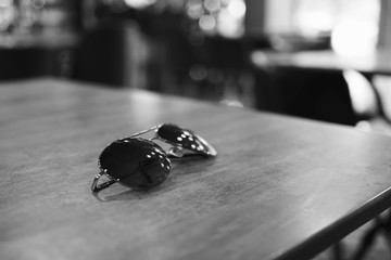 sunglasses on the wooden table in the restaurant in black and white color