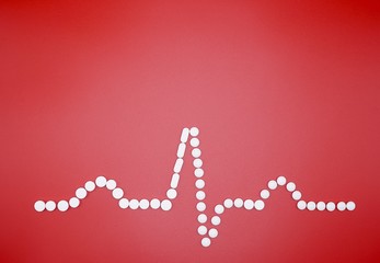 picture of electrocardiography made by white pills on red background