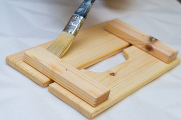 Girl varnishes a wooden detail.