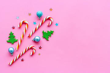 New Year design. Christmas candy cane, festive tree and balls on pink backgound top-down copy space