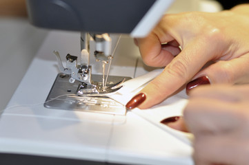 Fototapeta na wymiar Sewing machine. At work, a girl with a beautiful manicure in her hands.