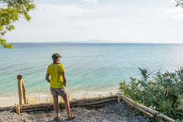 Tourist enjoying beautiful Greek landscapes during summer trip and vacations. Adult caucasian woman standing on top of hill looking at distance thoughtfully. Horizontal color photography.