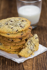 Old wooden table with fresh Chocolate Chip Cookies (close-up shot; selective focus)