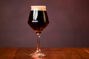 Glass of dark beer on the counter table in bar. Alcohol drink. Food photography concept, copy space.