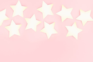 Golden stars on soft light pastel pink background as border, copy space, top view.