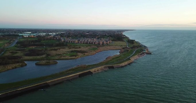 ascending drone footage over Essex coastline garrison uk army base mod shoeburyness artillery school now converted into housing estate clear crisp winter sunrise in December
