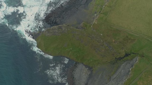 Aerial Birdview shot of epic thrilling landscape cliffs of moher while waves rolling onto rocky coast beach ireland