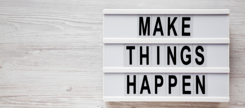 'Make things happen' words on a modern board on a white wooden background, overhead view. Top view, from above, flat lay. Copy space.