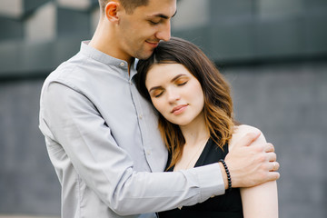 beautiful couple in love in black and white clothes hugging. The girl closed her eyes with pleasure