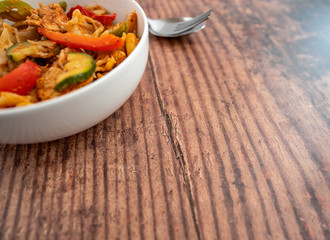  Selective focus of a spicy chicken and pasta dinner on a wooden background with copy space
