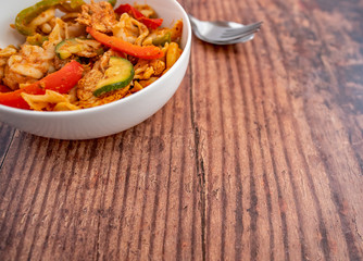 Selective focus of a spicy chicken and pasta dinner on a wooden background with copy space