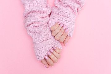 Female hands manicure close up view on pink knitted sweater background. Nail painting effects. Manicure salon banner concept