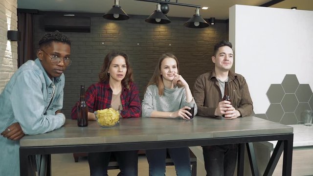 Group of best friends drinking beer and preparing to watch a movie or waiting for the broadcast of the game on TV in the living room