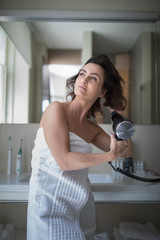 Beautiful young woman styling her her in her bathroom, in the morning