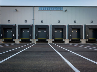 Warehouse exterior with loading ramps and slots for trucks to park - modern industry warehouse...