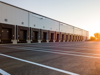 Warehouse exterior with loading ramps and slots for trucks to park - modern industry warehouse storage building.