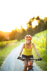 Pretty, young woman biking on a mountain bike enjoying healthy active lifestyle outdoors in summer...