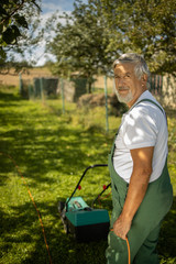 Senior gardenr gardening in his permaculture garden - mowing the lawn