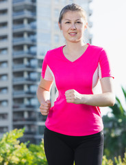 Adult female in pink T-shirt is jogging