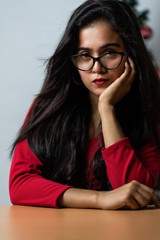Elegant lady in red dress over christmas tree lights background.