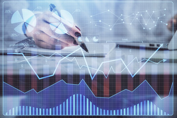 Double exposure of woman's hands making notes with forex graph hologram. Concept technical analysis.