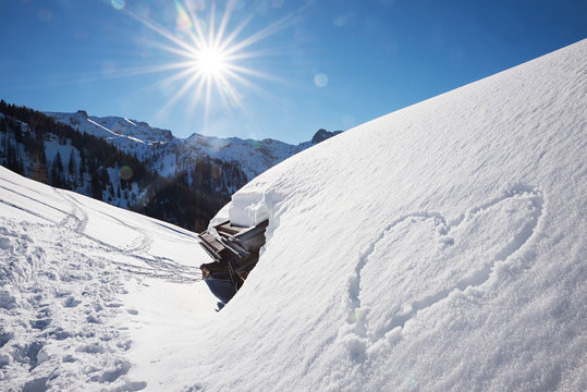 bright sunny winter landscape tirol, snow covered alp hut and love heart