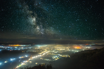 Starry sky over the night city in the fog