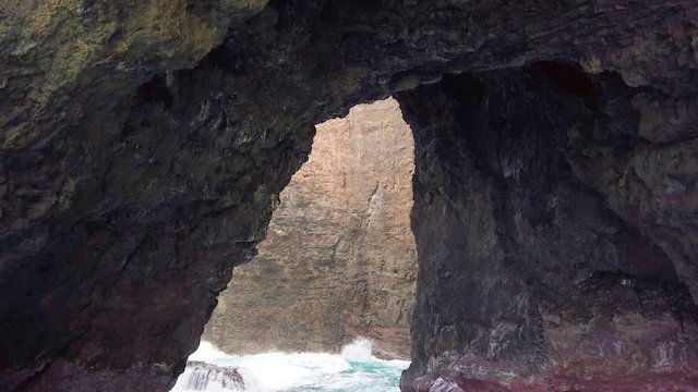 HD Hawaii Kauai Boating on the ocean floating near rock arch with rock wall background slowly  backing away from arch