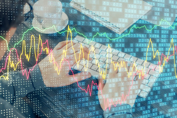 Double exposure of graph with man typing on computer in office on background. Concept of hard work.
